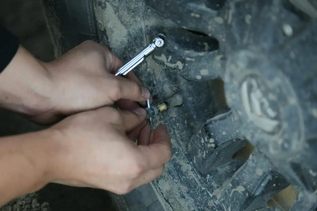 Close-up of hands using a socket wrench to tighten a bolt on a dirty metal surface on a vehicle part.