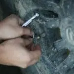 Close-up of hands using a socket wrench to tighten a bolt on a dirty metal surface on a vehicle part.
