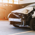 Car with front-end collision showing severe car frame damage inside an auto repair shop.